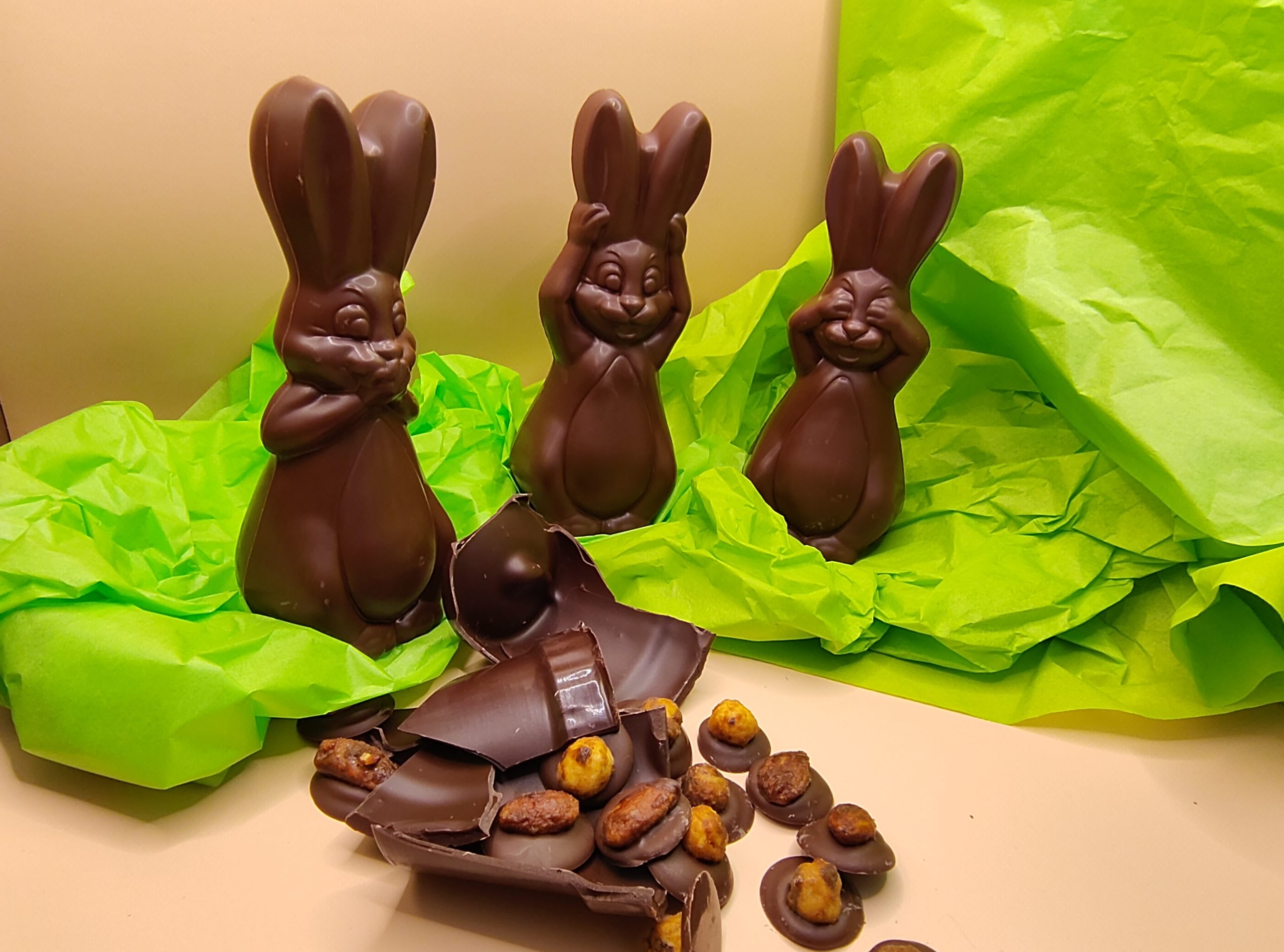 Trois lapins se cachent les yeux, les oreilles et la bouche autour d'un pot en chocolat cassé.
