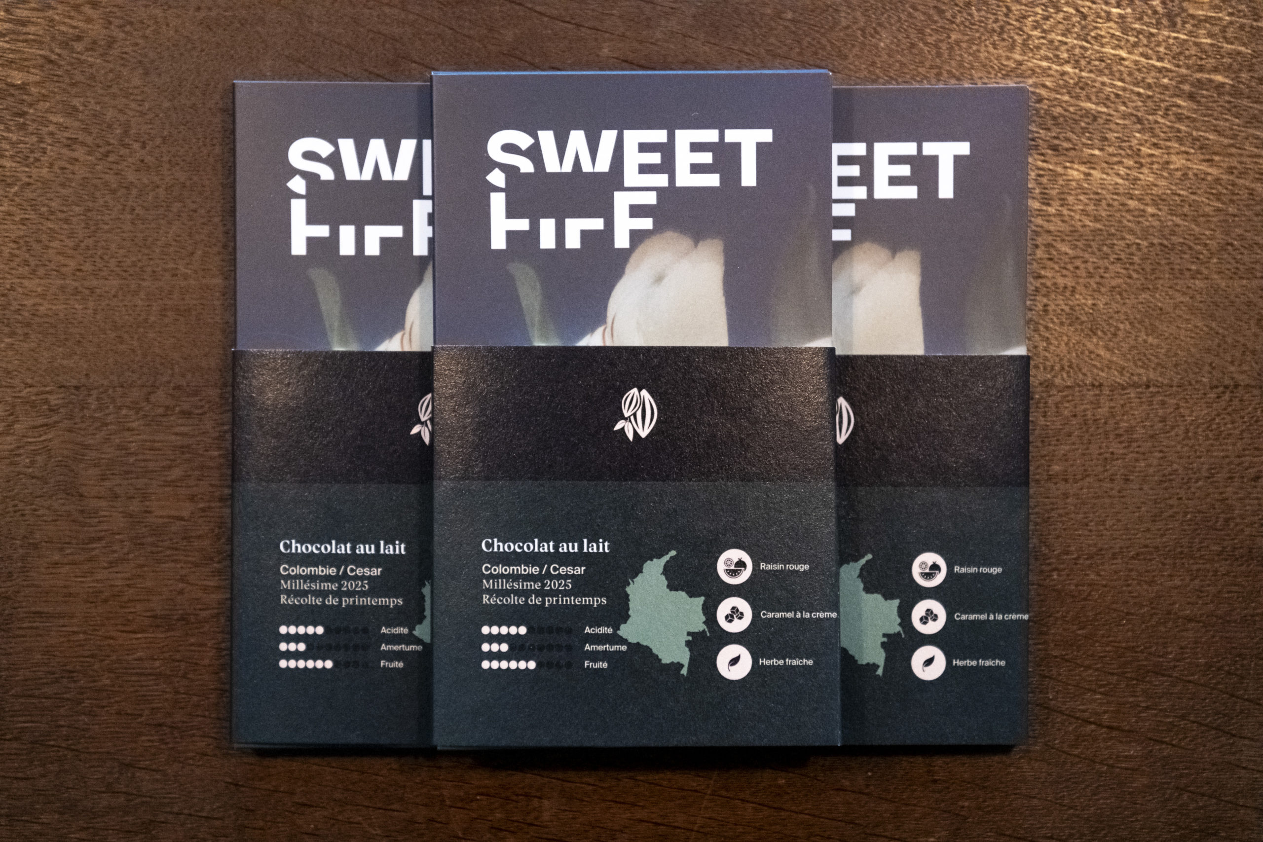Trois tablettes de chocolat Sweet FIFF. Sur le fourreau, on voit les informations "Chocolat au lait, Colombie, millésime 2025"